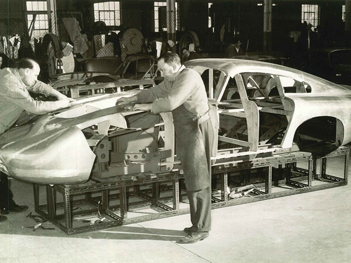 Master sheet metal worker Bert Brookes, in apron, affixes the magnesium/aluminum alloy panels to DP215 in 1963 (Credit - Courtesy of Ted Cutting/Aston Martin Lagonda).